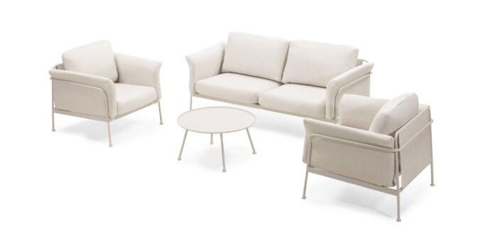 „Marinelli Beige“ lauko baldų komplektas su sofa, foteliais ir apvaliu stalu, pastatytas šviesioje terasoje.