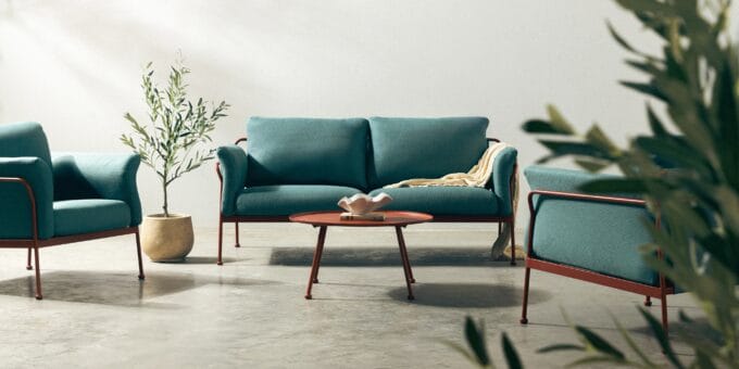Marinelli turquoise lauko baldų komplektas su dviviete sofa, dviem foteliais ir apvaliu stalu modernioje terasos aplinkoje